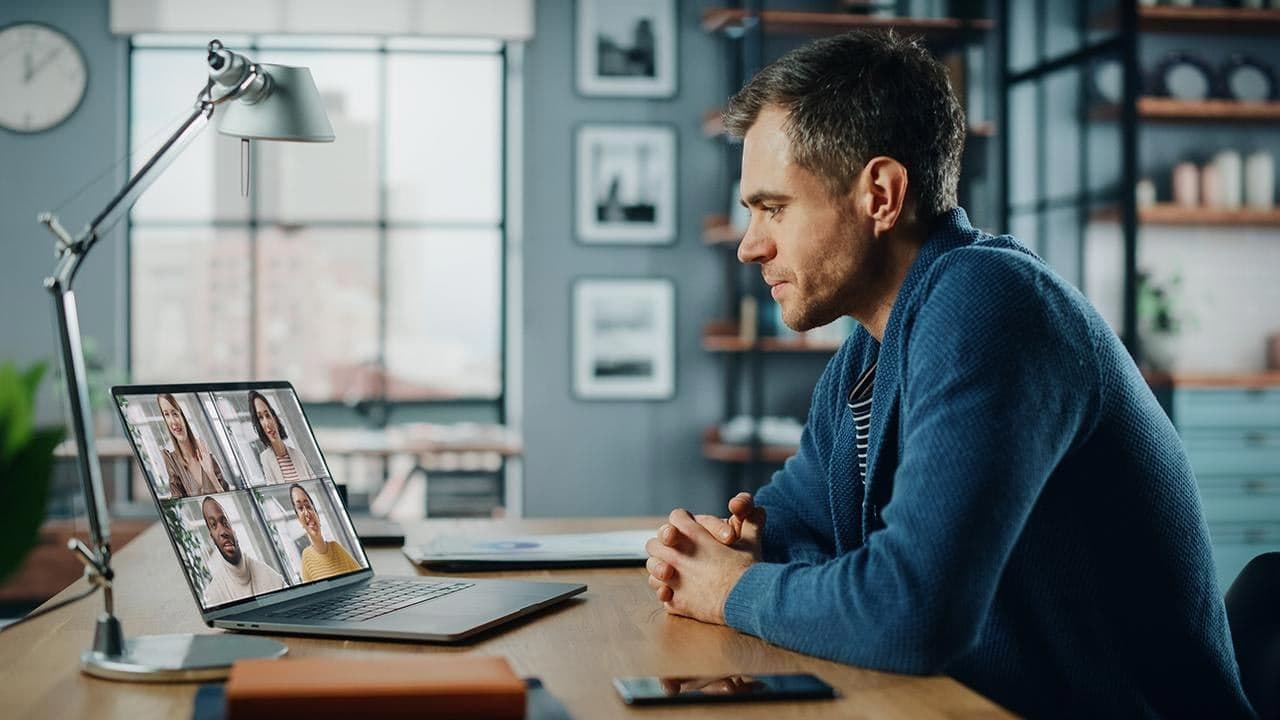 A man in a blue jumper on a video call.